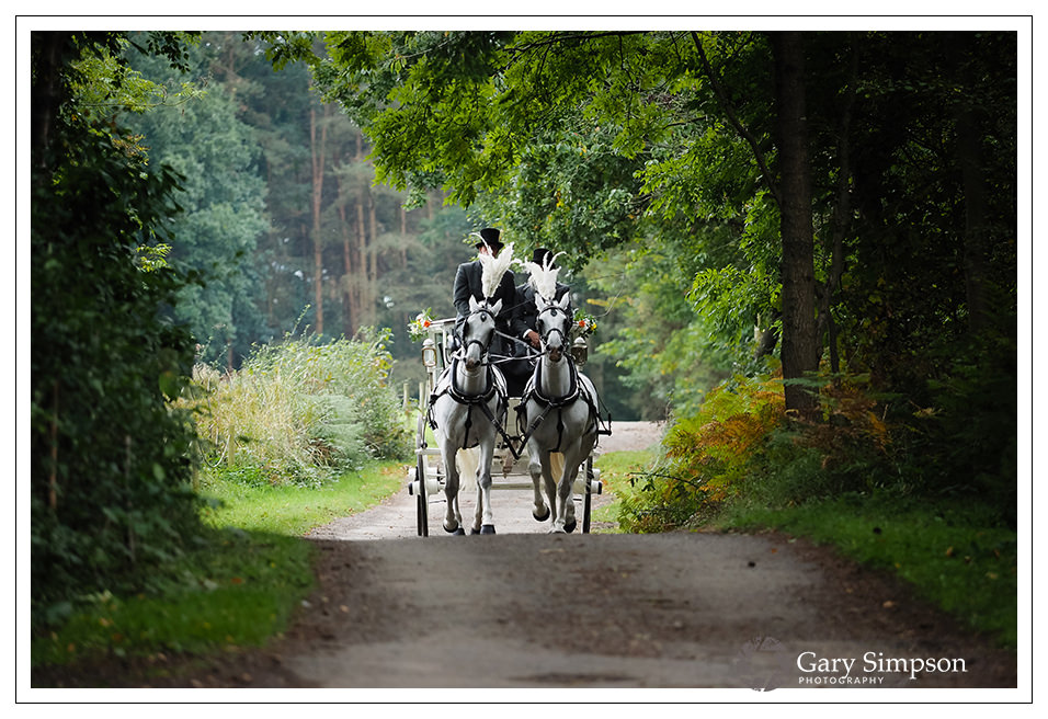 bride arriving in a horse drawn carriage at camp katur in north yorkshire