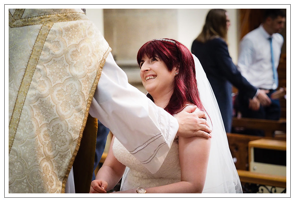 The bride shares a joke with the priest at St Wilfred's church