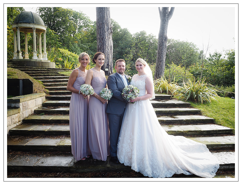 bride and groom portrait with the bridesmaids on the gardens of rushpool hall
