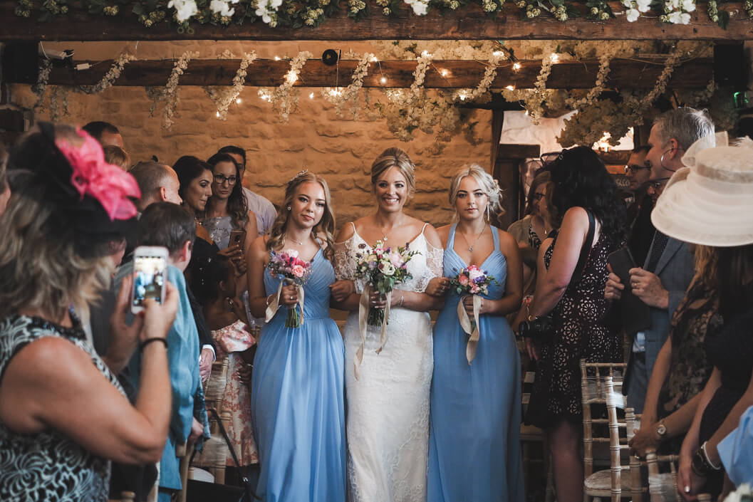 bride and bridesmaids entering the old barn at crossbutts stables for the wedding ceremony